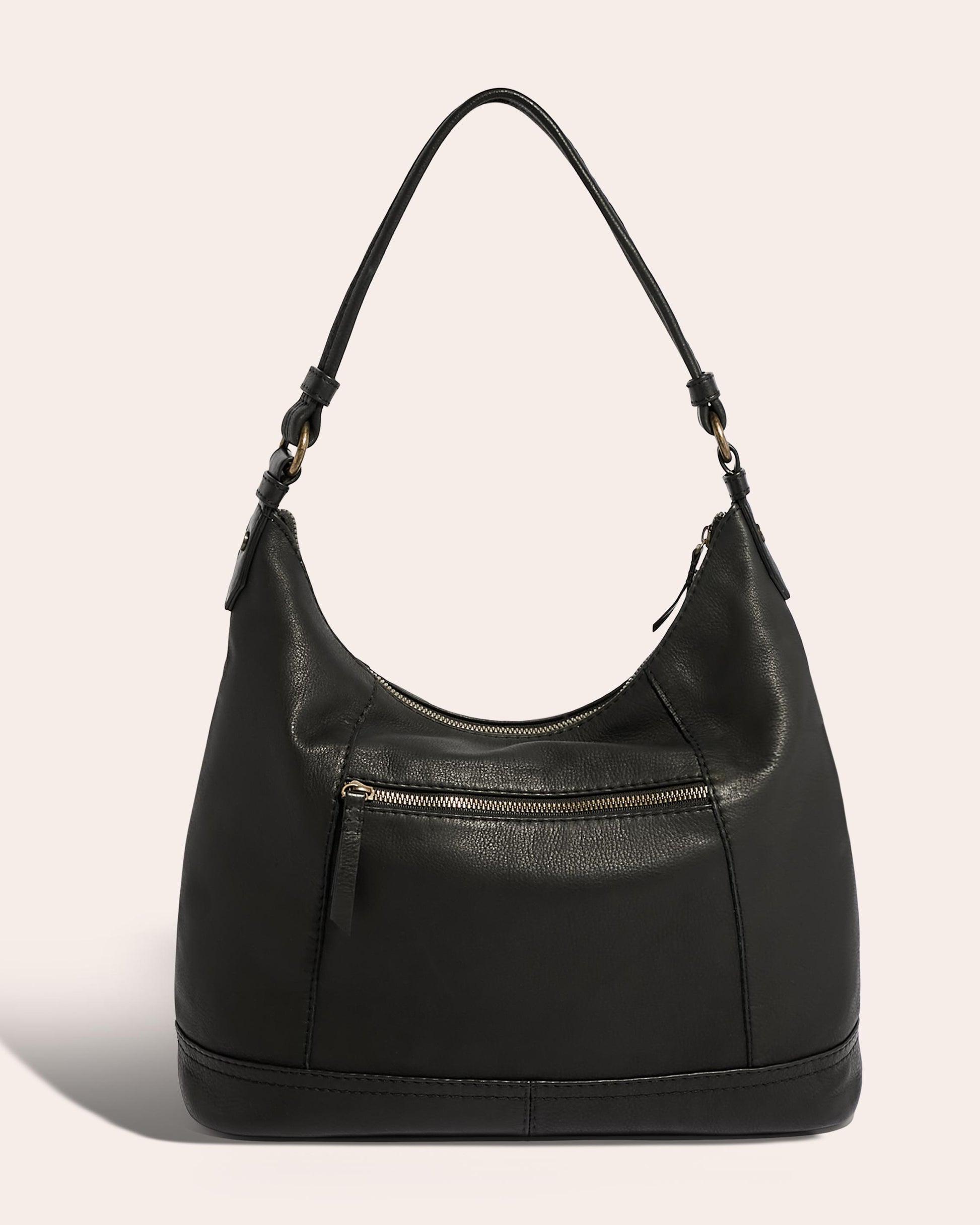 The Hudson Hobo by American Leather Co. is a black shoulder bag with a slouchy design, featuring a single strap and front zip pocket. It is crafted from genuine American leather and accented with antiqued brass hardware against a neutral beige background.